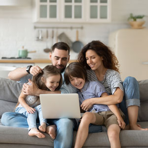 A family gathered on a couch, engaging with a laptop, symbolizing collaboration in understanding parenting plans - The Family Law Firm Of Tampa Bay