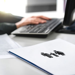 Close-up of a person typing on a keyboard with a family icon document in the foreground. - The Family Law Firm Of Tampa Bay